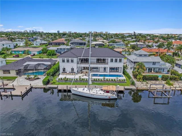 Aerial perspective of suburban area with a pool area and a large body of water