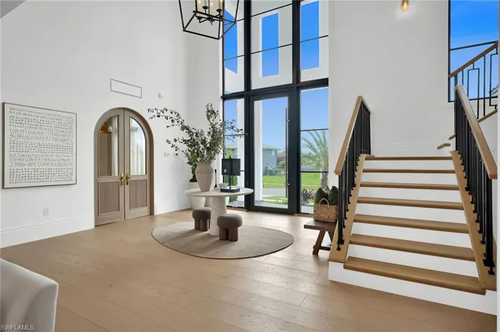 Entryway featuring arched walkways, hardwood / wood-style flooring, stairway, a chandelier, and a high ceiling