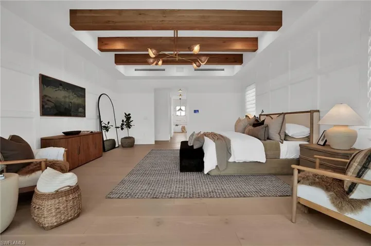 Bedroom featuring beam ceiling, a decorative wall, wood finished floors, and a chandelier