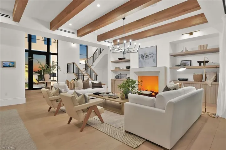 Living area featuring built in features, stairs, beamed ceiling, a chandelier, and recessed lighting
