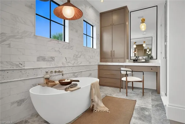 Master Bathroom featuring tile walls, a freestanding tub, and vanity