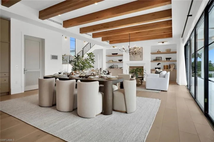 Dining area with beamed ceiling, a chandelier, a fireplace, and stairs
