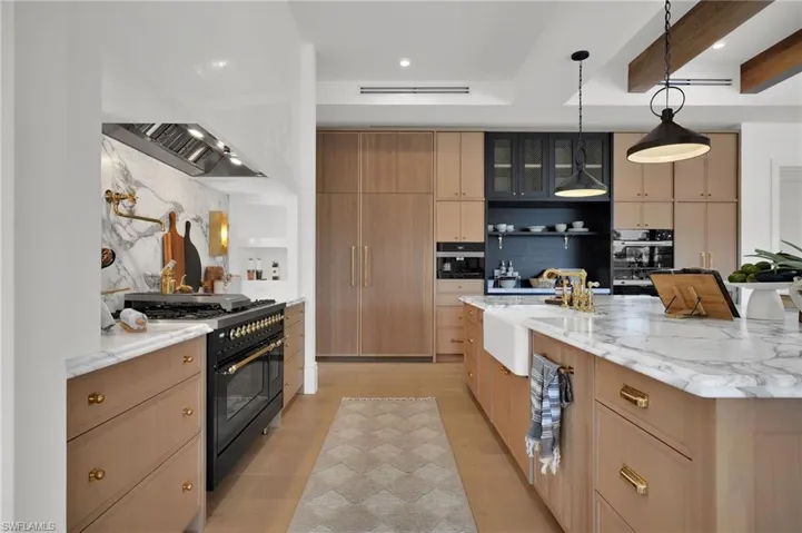 Kitchen featuring light stone counters, black appliances, decorative light fixtures, open shelves, and recessed lighting