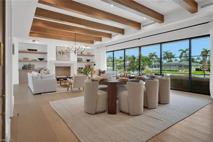 Dining room featuring beam ceiling, a chandelier, light wood-style floors, and a fireplace