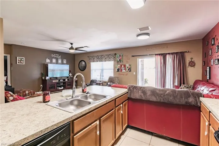 Kitchen with kitchen peninsula, dishwasher, ceiling fan, sink, and light tile floors