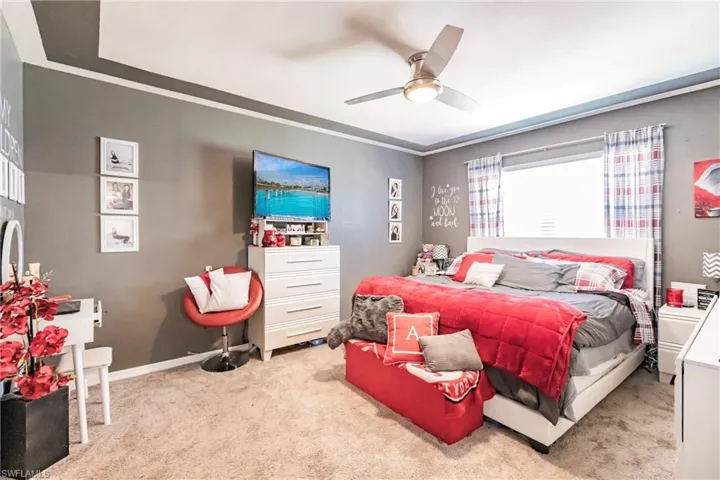 Bedroom with ceiling fan, light colored carpet, and ornamental molding