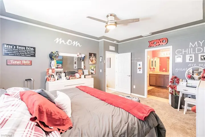 Bedroom featuring light carpet, connected bathroom, ornamental molding, and ceiling fan