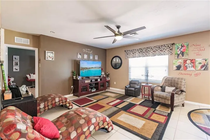 Living room with ceiling fan and light tile floors