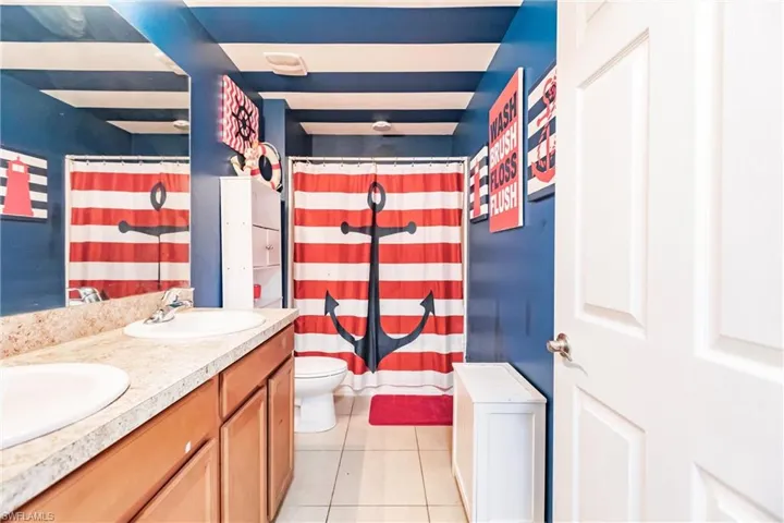 Bathroom with tile floors, dual sinks, oversized vanity, and toilet