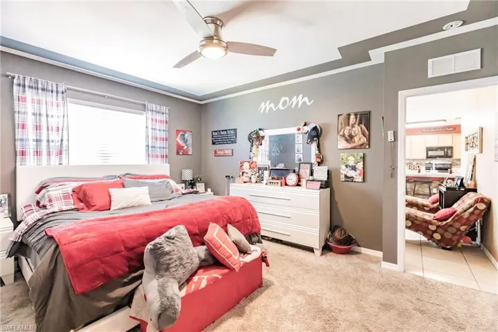Bedroom with light colored carpet, ornamental molding, and ceiling fan
