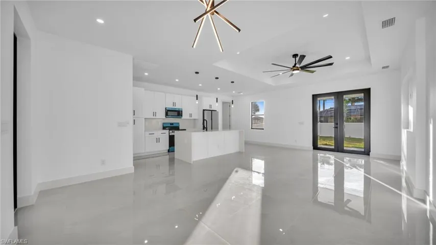 Unfurnished living room featuring recessed lighting, a tray ceiling, and ceiling fan