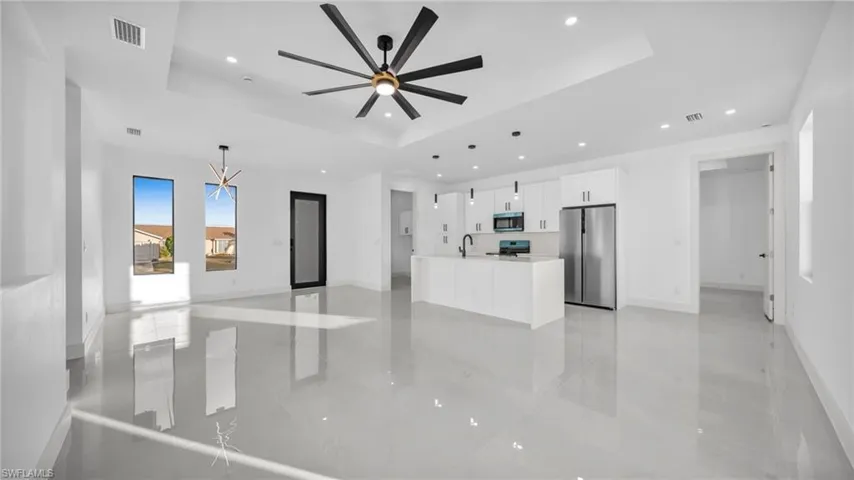 Unfurnished living room featuring a raised ceiling, recessed lighting, light marble finish flooring, and a ceiling fan