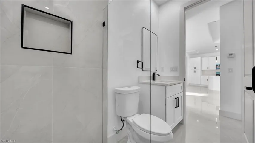 Full bath featuring vanity, light marble finish flooring, and a marble finish shower