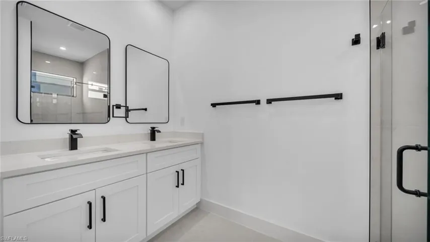 Full bathroom with a shower stall, double vanity, and light tile patterned floors