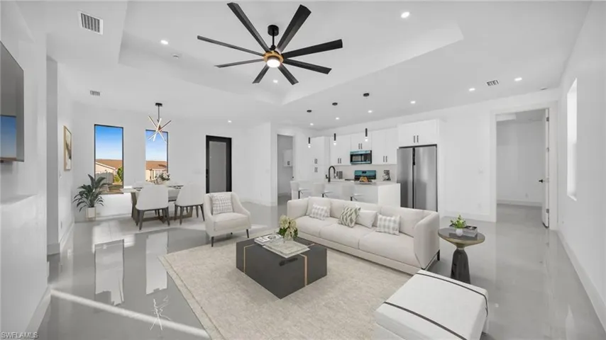 Living area with a tray ceiling, recessed lighting, a chandelier, and a ceiling fan