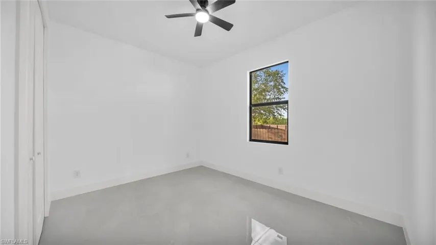 Unfurnished room featuring ceiling fan and baseboards