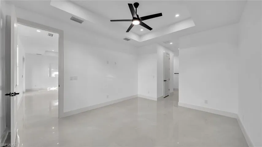 Empty room featuring a tray ceiling, recessed lighting, and ceiling fan