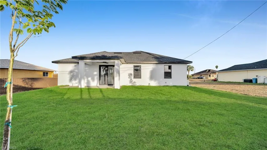 Back of property featuring stucco siding, a lawn, and ceiling fan
