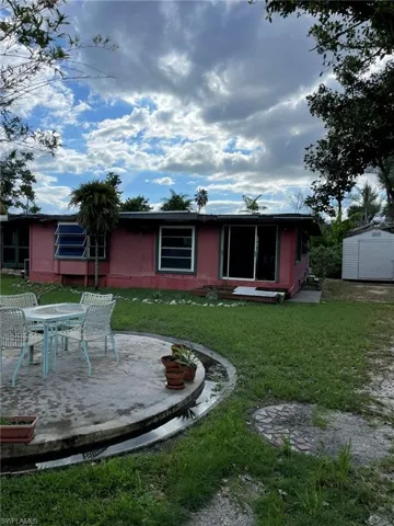 Rear view of property featuring a yard, a patio area, and a storage shed