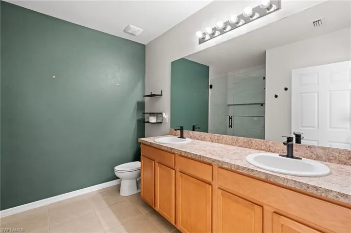 Bathroom featuring vanity, toilet, an enclosed shower, and tile patterned flooring