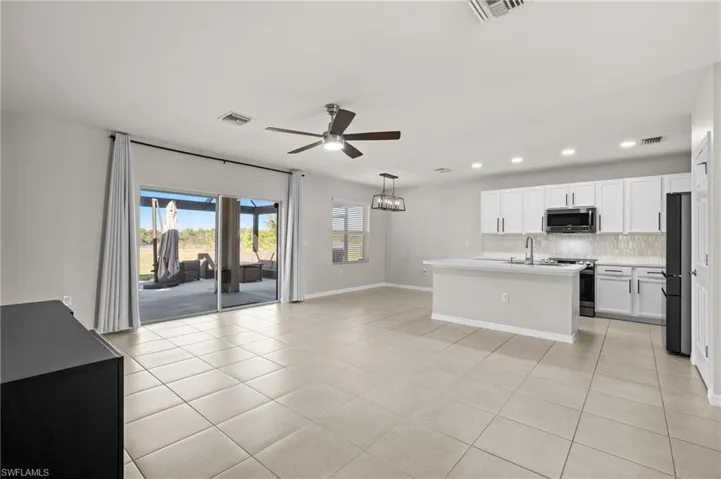 Kitchen featuring white cabinetry, backsplash, light tile patterned floors, and stainless steel appliances