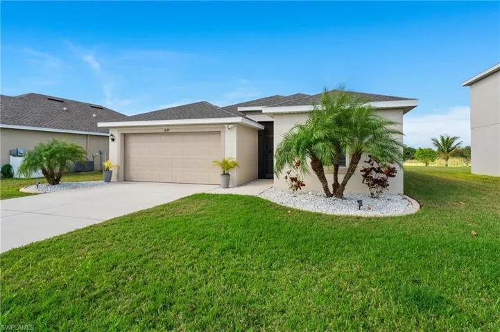 View of front of property with a garage, a front lawn, and central air condition unit