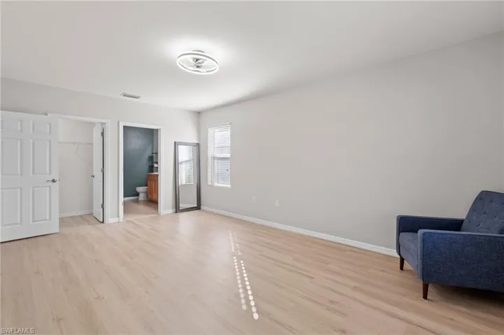Bedroom with ensuite bath, a spacious closet, a closet, and light hardwood / wood-style flooring