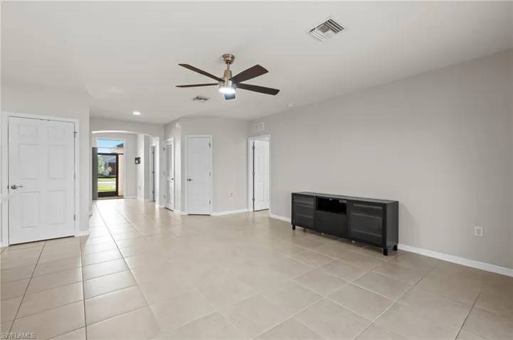 Empty room with ceiling fan and light tile patterned floors