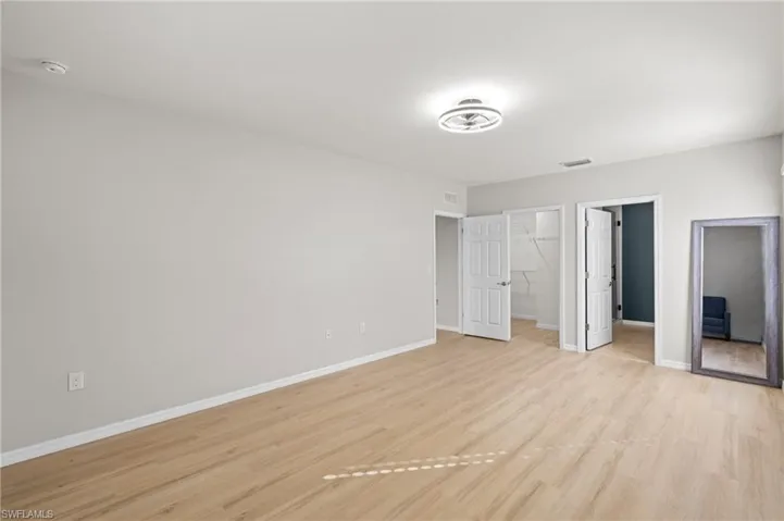 Unfurnished bedroom featuring a spacious closet and light hardwood / wood-style floors