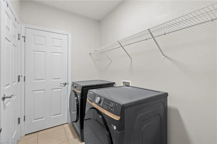 Clothes washing area featuring light tile patterned flooring and independent washer and dryer