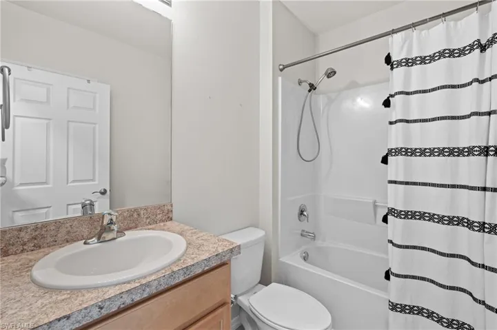 Full bathroom featuring shower / bath combination with curtain, vanity, and toilet