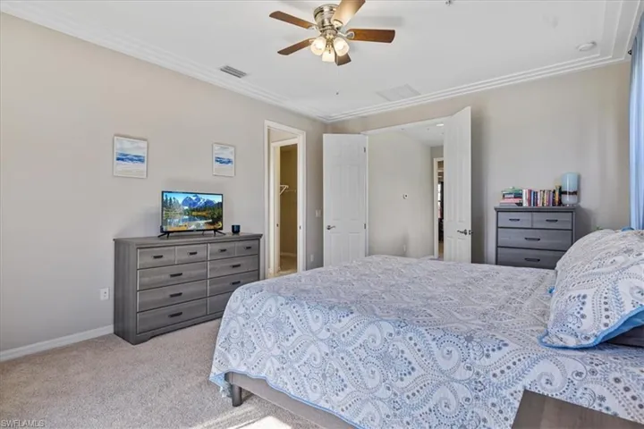 Carpeted bedroom featuring ceiling fan and crown molding