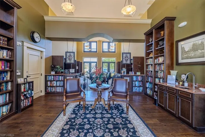 Library with sink, dark wood-type flooring, a high ceiling, built in features, and ornamental molding