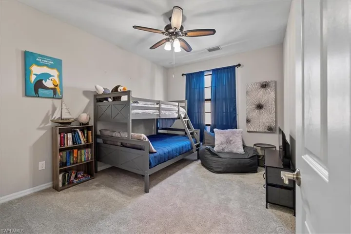 Bedroom with ceiling fan and light colored carpet