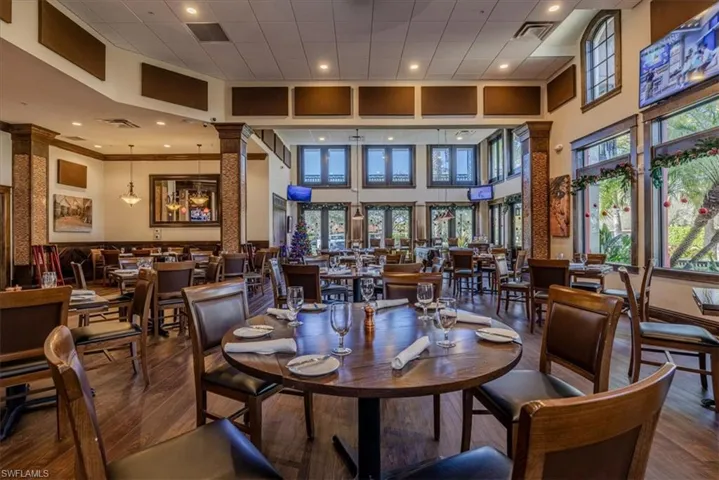 Dining area with hardwood / wood-style floors, plenty of natural light, ornate columns, and a high ceiling