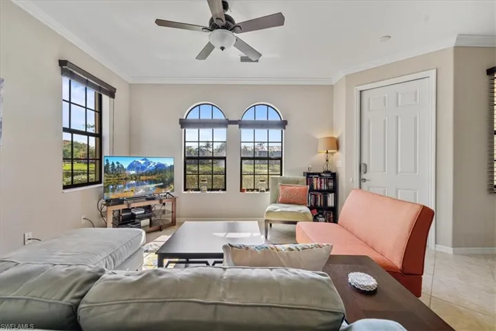 Living room featuring light tile patterned floors, crown molding, ceiling fan, and a healthy amount of sunlight