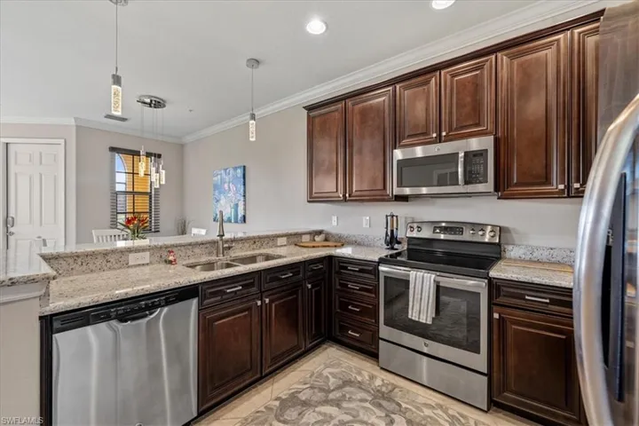 Kitchen featuring decorative light fixtures, kitchen peninsula, sink, and appliances with stainless steel finishes