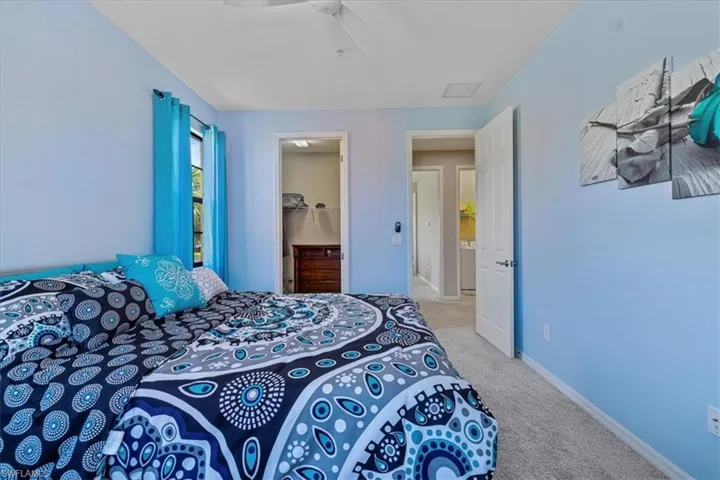 Carpeted bedroom featuring ceiling fan, a spacious closet, and a closet