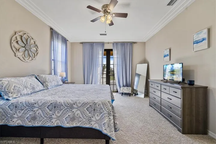Carpeted bedroom featuring ceiling fan and ornamental molding