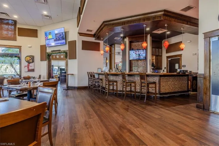 Bar with hardwood / wood-style floors, pendant lighting, and a high ceiling