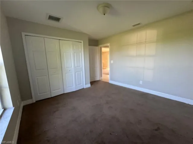 Unfurnished bedroom featuring a closet and dark colored carpet