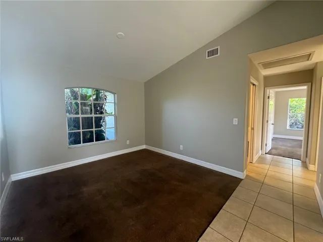Empty room featuring vaulted ceiling and tile flooring