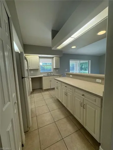 Kitchen featuring sink, white cabinets, a wealth of natural light, and light tile floors