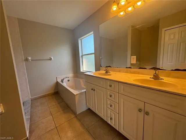 Bathroom featuring a bathtub, double sink, oversized vanity, and tile floors
