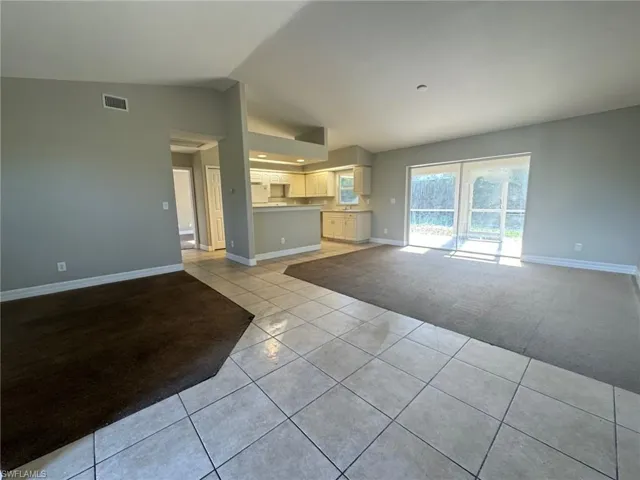 Unfurnished living room featuring vaulted ceiling and light tile flooring