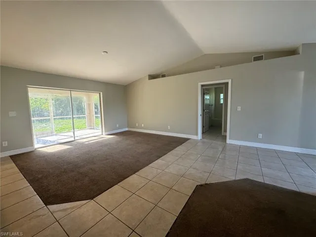 Unfurnished room featuring vaulted ceiling and light tile floors