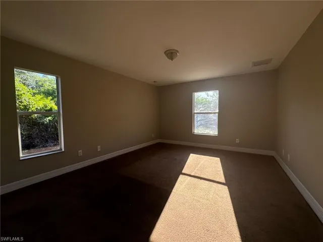 Carpeted spare room featuring a healthy amount of sunlight