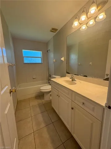 Full bathroom featuring tiled shower / bath, vanity, toilet, and tile floors