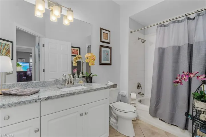 Bathroom with tile patterned flooring, toilet, vanity, and shower / bathtub combination with curtain