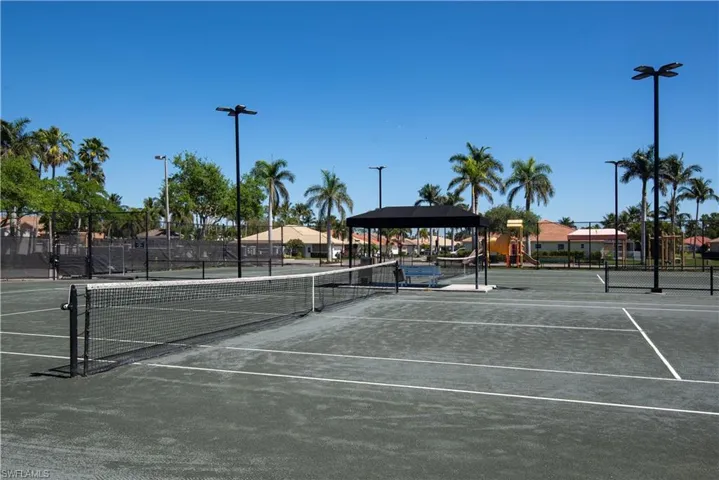 View of tennis court with playground community and fence